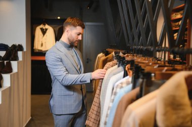 Gülümseyen, seyir ve klasik seçme Modern genç yakışıklı işadamı uygun takım elbise dükkanı.