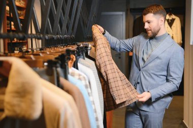 Gülümseyen, seyir ve klasik seçme Modern genç yakışıklı işadamı uygun takım elbise dükkanı.