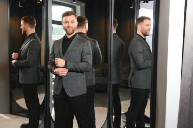 Gülümseyen, seyir ve klasik seçme Modern genç yakışıklı işadamı uygun takım elbise dükkanı.