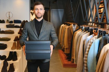 Giysi mağazasında içinde yeni kıyafetler ya da ayakkabılar olan kutular tutan mutlu müşteriler..