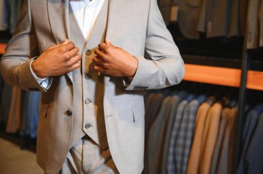 Premium erkek giyim mağazasında şık takım elbiseli Afrikalı bir işadamı.