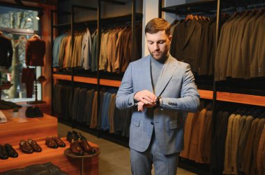 Gülümseyen, seyir ve klasik seçme Modern genç yakışıklı işadamı uygun takım elbise dükkanı.