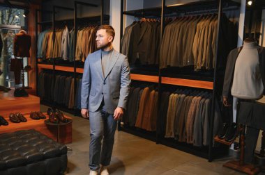 Gülümseyen, seyir ve klasik seçme Modern genç yakışıklı işadamı uygun takım elbise dükkanı.