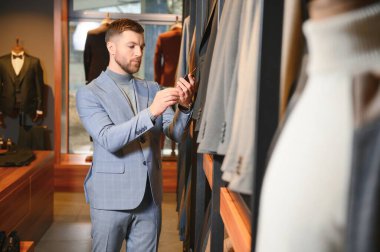 Gülümseyen, seyir ve klasik seçme Modern genç yakışıklı işadamı uygun takım elbise dükkanı.