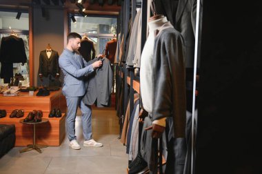 Gülümseyen, seyir ve klasik seçme Modern genç yakışıklı işadamı uygun takım elbise dükkanı.