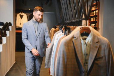 Gülümseyen, seyir ve klasik seçme Modern genç yakışıklı işadamı uygun takım elbise dükkanı.