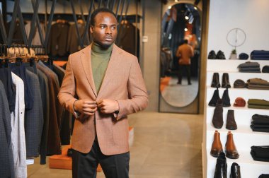 Premium erkek giyim mağazasında şık takım elbiseli Afrikalı bir işadamı.