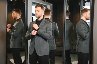 Gülümseyen, seyir ve klasik seçme Modern genç yakışıklı işadamı uygun takım elbise dükkanı.