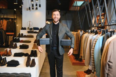 Giysi mağazasında içinde yeni kıyafetler ya da ayakkabılar olan kutular tutan mutlu müşteriler..