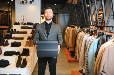 Afro-Amerikalı neşeli bir adam giyim mağazasında alışveriş torbaları taşıyor. Moda butiği..