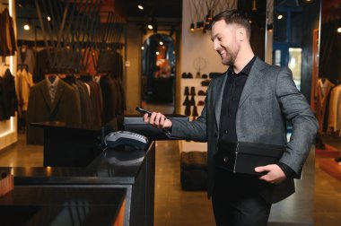 Afro-Amerikalı neşeli bir adam giyim mağazasında alışveriş torbaları taşıyor. Moda butiği..