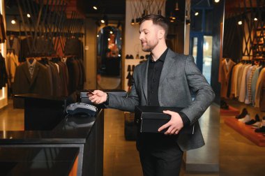 Kutular dolusu yeni kıyafet ve ayakkabı taşıyan ve kredi kartıyla ödeme yapan mutlu müşteriler..