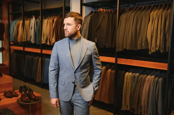 Gülümseyen, seyir ve klasik seçme Modern genç yakışıklı işadamı uygun takım elbise dükkanı.