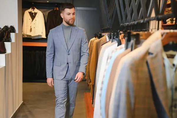 Gülümseyen, seyir ve klasik seçme Modern genç yakışıklı işadamı uygun takım elbise dükkanı.