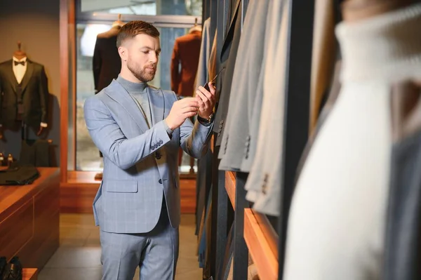 Gülümseyen, seyir ve klasik seçme Modern genç yakışıklı işadamı uygun takım elbise dükkanı.