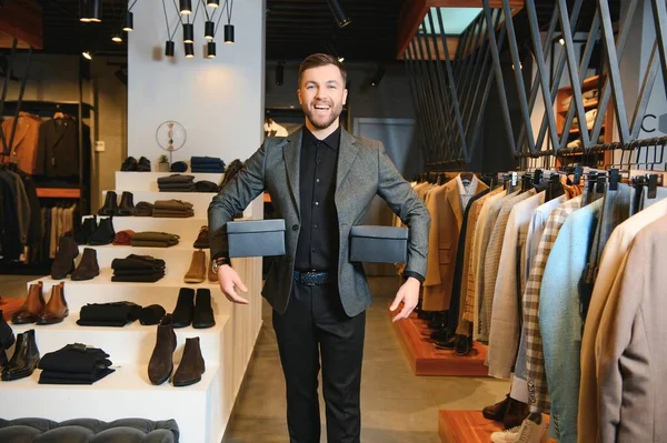 Giysi mağazasında içinde yeni kıyafetler ya da ayakkabılar olan kutular tutan mutlu müşteriler..