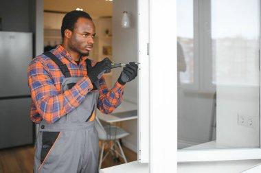 Evdeki oturma odasına plastik pencereler monte eden ya da ayarlayan işçi.