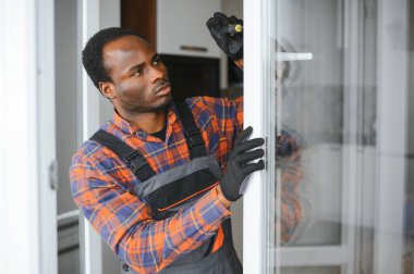 Afrikalı bir tamirci daireye metal-plastik pencereleri tamir eder, düzenler ya da yerleştirir.