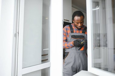 Evdeki oturma odasına plastik pencereler monte eden ya da ayarlayan işçi.