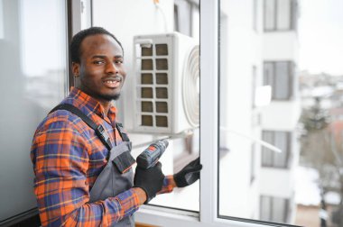 Profesyonel bir elektrikçi ağır klimayı tamir ediyor..