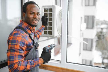 Profesyonel bir elektrikçi ağır klimayı tamir ediyor..