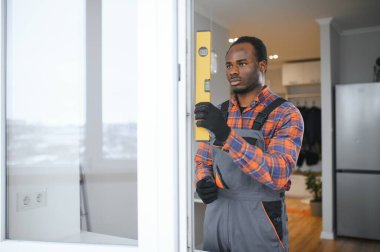 Evdeki oturma odasına plastik pencereler monte eden ya da ayarlayan işçi.