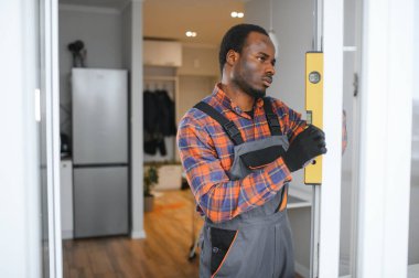 Evdeki oturma odasına plastik pencereler monte eden ya da ayarlayan işçi.