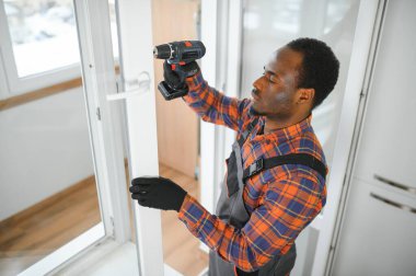 Evdeki oturma odasına plastik pencereler monte eden ya da ayarlayan işçi.