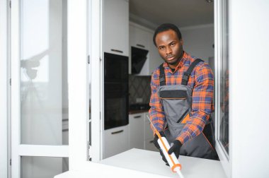 Evdeki oturma odasına plastik pencereler monte eden ya da ayarlayan işçi.