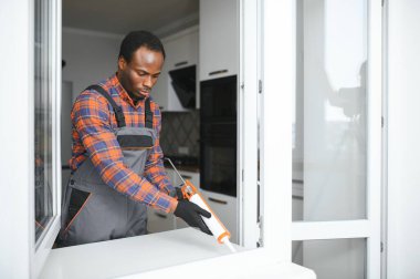Evdeki oturma odasına plastik pencereler monte eden ya da ayarlayan işçi.