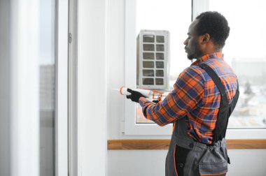 Evdeki oturma odasına plastik pencereler monte eden ya da ayarlayan işçi.