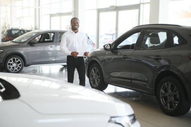 Genç Afro-Amerikan araba galerisi müdürü araç galerisinde duruyor..