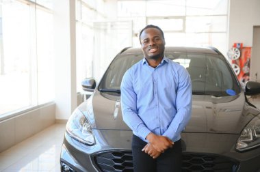 Yakışıklı adam yeni arabasının yanında duruyor ve gülümsüyor..