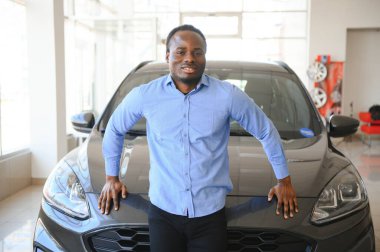 Yakışıklı adam yeni arabasının yanında duruyor ve gülümsüyor..