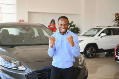 Yakışıklı adam yeni arabasının yanında duruyor ve gülümsüyor..