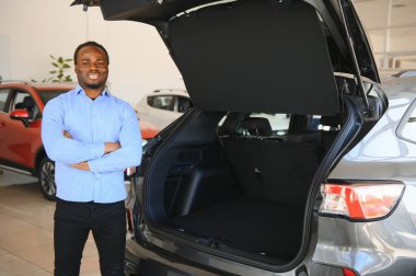 Yakışıklı adam yeni arabasının yanında duruyor ve gülümsüyor..