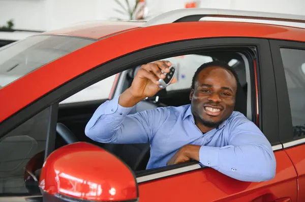 Happy Car Buyer, New Car Owner Concept. Portrait Of Excited Young African American Guy In Dealership Showroom.