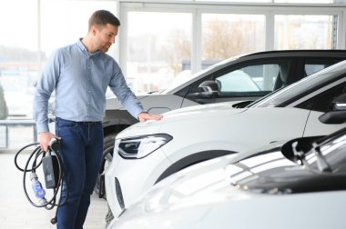 Galeride ilk elektrikli araba alan genç adam. Eko araba satışı kavramı.