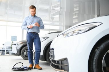 Galeride ilk elektrikli araba alan genç adam. Eko araba satışı kavramı.