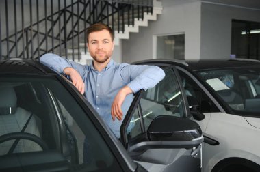 Delikanlı, galeride elektrikli araba satıyor. Aile için çevre dostu araba alma kavramı.