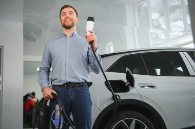 Galeride ilk elektrikli araba alan genç adam. Eko araba satışı kavramı.