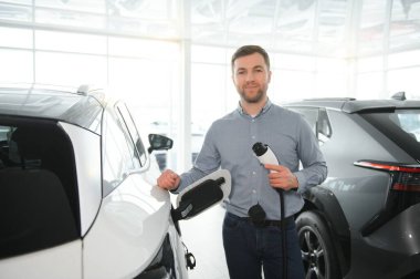 Galeride ilk elektrikli araba alan genç adam. Eko araba satışı kavramı.