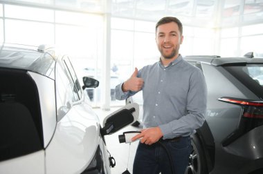 Galeride ilk elektrikli araba alan genç adam. Eko araba satışı kavramı.