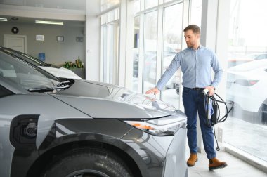 Galeride ilk elektrikli araba alan genç adam. Eko araba satışı kavramı.