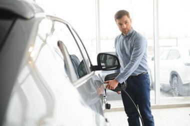 Galeride ilk elektrikli araba alan genç adam. Eko araba satışı kavramı.