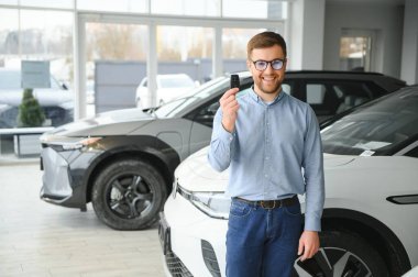 Elektrikli araba alma kavramı. Yakışıklı iş adamı galeride elektrikli arabanın yanında duruyor..