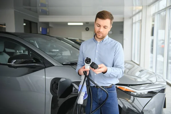 Delikanlı, galeride elektrikli araba satıyor. Aile için çevre dostu araba alma kavramı.