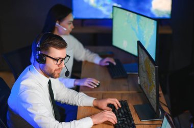 Tamirat merkezi. Seyrüsefer kontrol panosunda otururken kulaklıkla çalışan neşeli kadın ve erkek portresi.