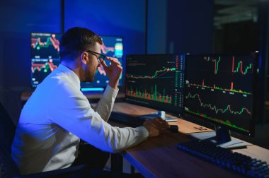 Gecenin geç saatlerinde borsa verilerini karşılaştıran iş adamı .