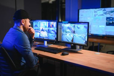 Erkek güvenlik görevlisi modern CCTV kameralarını içeride izliyor..